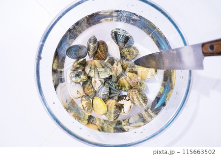 塩水の入ったボウルの中で砂抜きされているアサリ貝と包丁、料理の下準備 115663502