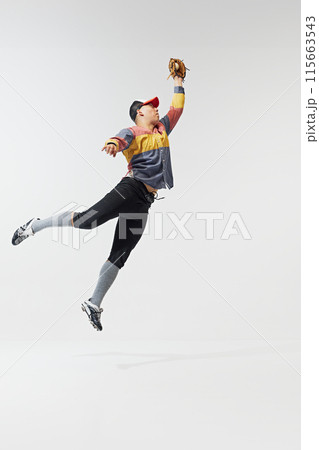 Full-length bottom view image of focused man, baseball player in motion, catching ball in mid-air pose isolated on white background. Full-length bottom view image of focused man, baseball player in motion, catching ball in mid-air pose isolated on white background. 115663543