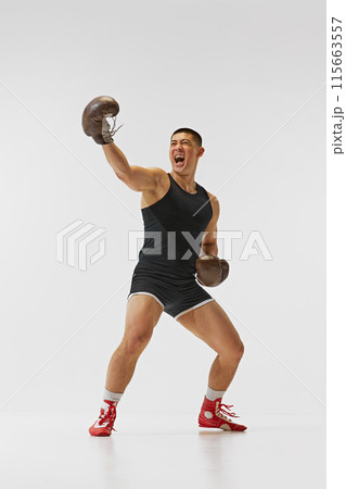 Achievement, success, victory. Full-length of emotions man, boxer in gloves showing his emotions after winning battle isolated on white background. 115663557