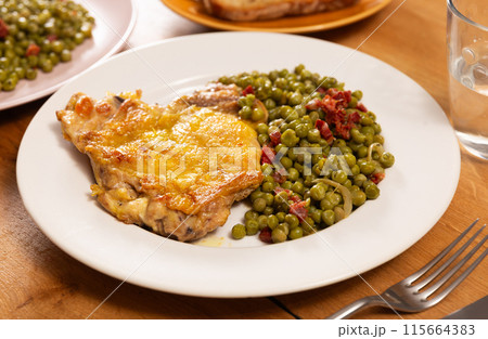 Delicious crispy chicken with peas as a side dish on a plate 115664383