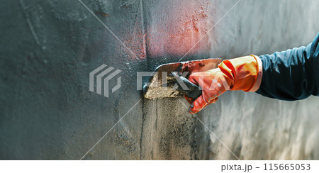 person is plastering cement on wall with a brush 115665053