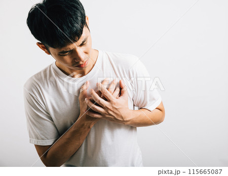 Portrait Asian young man holding his arms around his chest suffering because of a heart attack studio isolated white background, Happy lifestyle men chest pain health discomfort heart problems 115665087