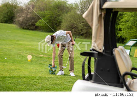 Young golfer in a cap on a field in a golf club 115665152
