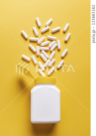 White medicine capsules on yellow background 115665162