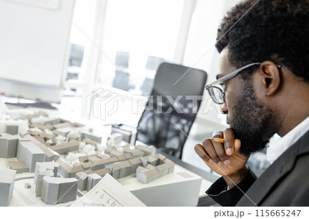 Innovative man architect updating blueprints before presentation n his workplace 115665247