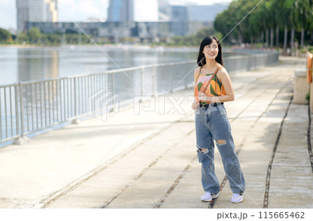 A happy young woman, enjoying a stroll on an urban path, dressed in an orange shirt. 115665462