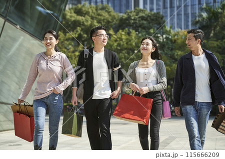 group of young asian people talking chatting conversing while walking on street with shopping bags 115666209