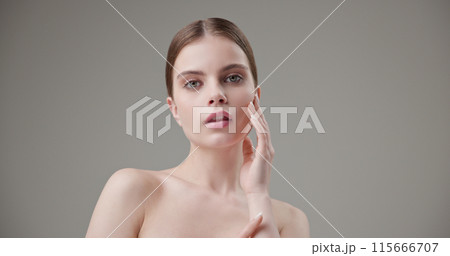 Beauty, health, cosmetics, anti-aging therapy and skin care concept - young beautiful brunette Caucasian woman posing and looking at the camera with a calm confident look like in a mirror 115666707