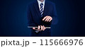 Businessman in a suit using a tablet, standing against a dark background. Ideal for business, technology, and professional concept 115666976