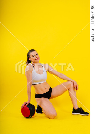 Fitness happy fit woman standing holding a medicine ball. Slim caucasian cross fit woman with fitness ball Fitness happy fit woman standing holding a medicine ball. Slim caucasian cross fit woman with fitness ball 115667190