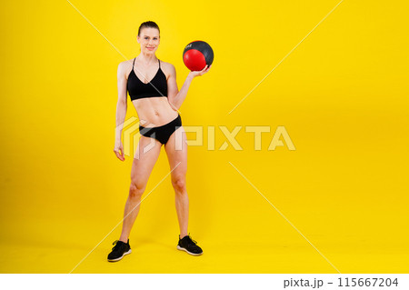 Fitness happy fit woman standing holding a medicine ball. Slim caucasian cross fit woman with fitness ball 115667204