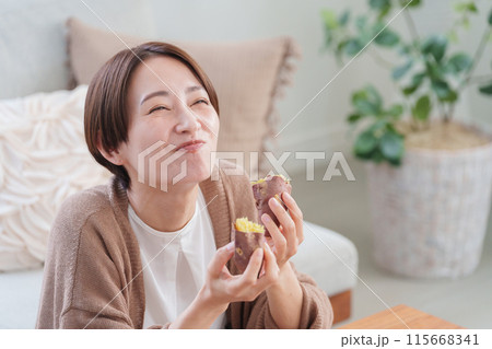 焼き芋を食べる女性（秋・食事・さつまいも） 115668341