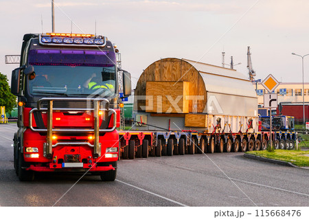 Truck with a very long specialized multi-axle trailer carries a very heavy oversize cargo 115668476
