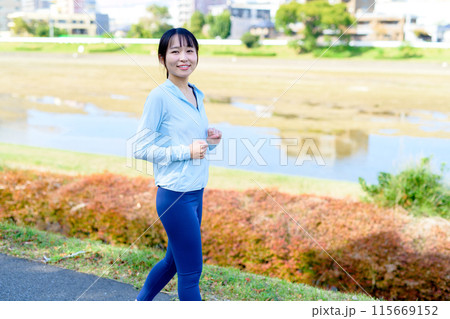 川沿いの街中をジョギングする若い女性　ボディメイク　ダイエット　 115669152