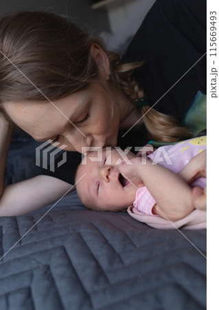 A tender moment of a mother kissing her newborn baby, capturing pure love and warmth 115669493
