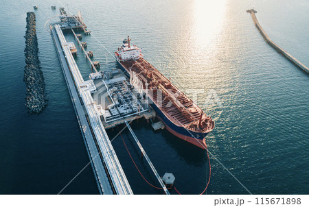 Aerial view of a large oil tanker docked at a pier in the port in process of loading. 115671898