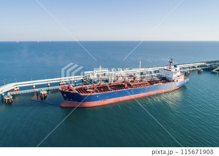 Aerial view of a large oil tanker docked at a pier in the port in process of loading. 115671908