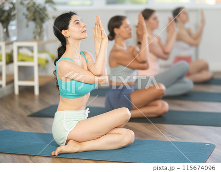 Young girl performing Cow face pose with eagle arms at yoga class 115674096