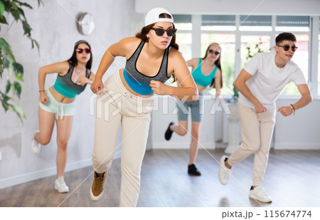 Group of young girls in dark glasses and ball cap and guy dance jazz-funk in fitness club. Group of young girls in dark glasses and ball cap and guy dance jazz-funk in fitness club. 115674774