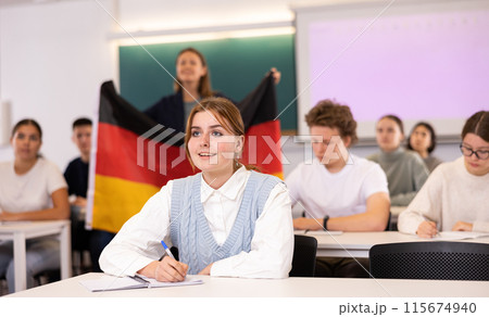 Teacher stands behind students with German flag Teacher stands behind students with German flag 115674940