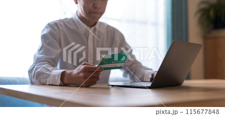 通帳を見る男性 115677848