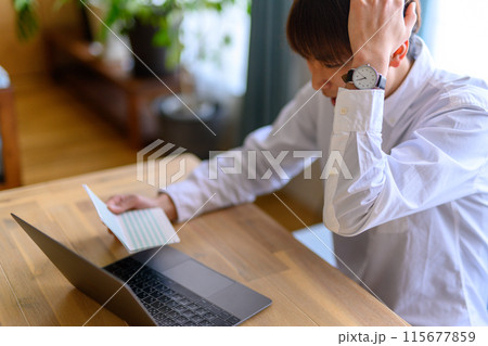 通帳を見る男性 115677859