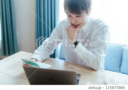 通帳を見る男性 115677860