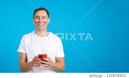 Polish supporter looking at his mobile smiling and showing it. 115678541