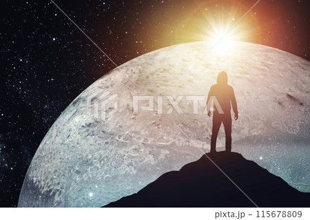 Silhouette of a man standing on the top of a mountain against the backdrop of the planet. Elements of this image furnished by NASA 115678809