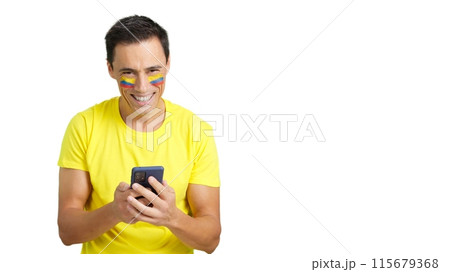 Colombian supporter looking at his mobile smiling and showing it. 115679368