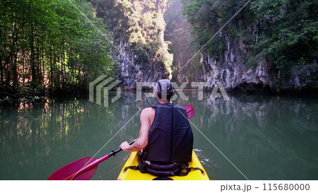 Man leisurely navigates kayak admiring wild nature 115680000