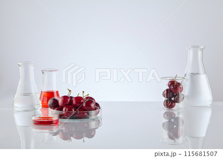 Advertising photo of cherry fruit extract products in laboratory, blank space in center for product presentation, decorated with lab items and fresh cherry on both sides. Front view photo, copy space 115681507