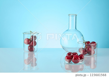 Pastel blue background photo with fresh sweet cherry contained in lab glassware. Photo of front angle shot with many spaces for adding elements of designing and text 115681568