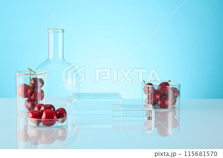 Two rectangular glass podiums in different, displayed on the table with lab instruments and fresh cherry around. Photograph of front angle, empty space for text 115681570