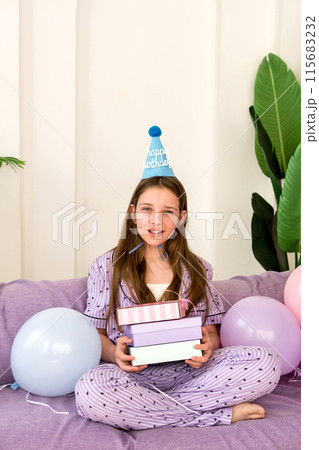 Young girl celebrating birthday at home with presents and balloons. 115683232