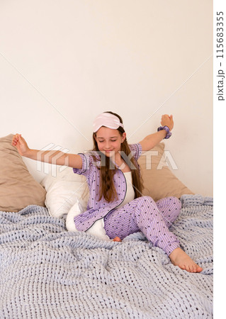 Girl stretching joyfully on bed in morning light Girl stretching joyfully on bed in morning light 115683355