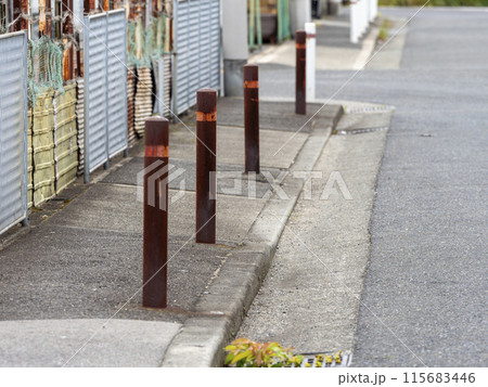 歩道に設置された錆びたボラード 115683446