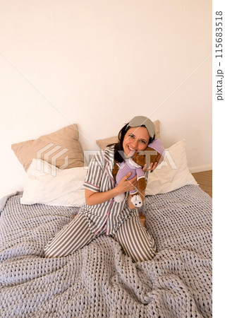 Woman with stuffed toys posing playfully on bed. Woman with stuffed toys posing playfully on bed. 115683518