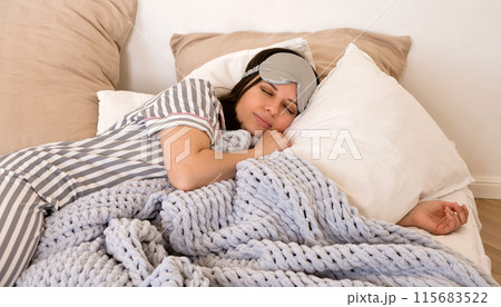 Woman sleeping peacefully in bed wearing eye mask. Woman sleeping peacefully in bed wearing eye mask. 115683522