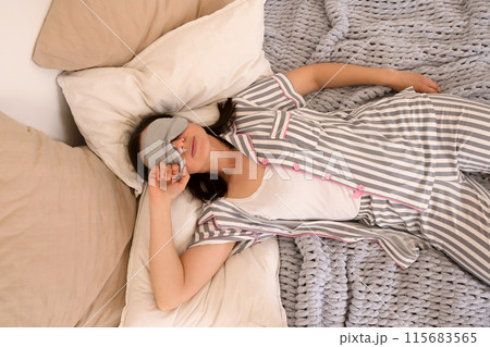Woman sleeping peacefully in bed with eye mask. Woman sleeping peacefully in bed with eye mask. 115683565