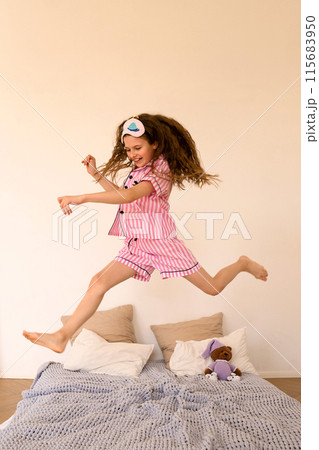 Child jumping on bed in playful mood in bedroom. Child jumping on bed in playful mood in bedroom. 115683950
