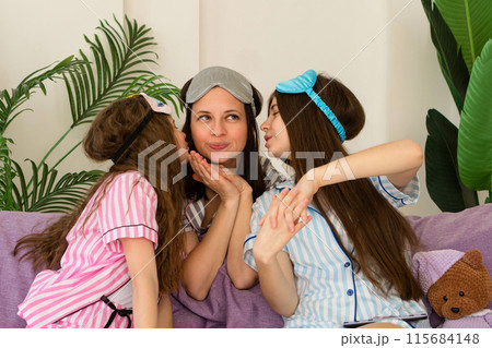 Mother receiving kisses from her daughters at home. Mother receiving kisses from her daughters at home. 115684148