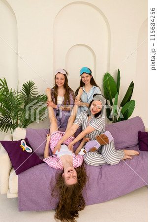 Playful family moment with mother and daughters on couch. Playful family moment with mother and daughters on couch. 115684256