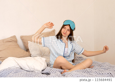 Teenager stretching with sleep mask pushed up on her forehead. Teenager stretching with sleep mask pushed up on her forehead. 115684491