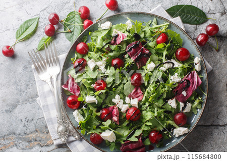 Spicy Cherry salad with arugula, radicchio and feta cheese dressed with balsamic dressing close-up in a plate. Horizontal top view 115684800