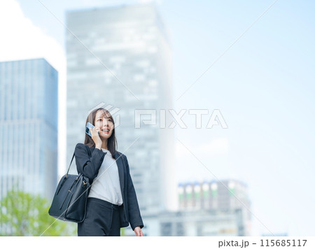 スマホで通話しながら都市を歩くキャリアウーマン スマホで通話しながら都市を歩くキャリアウーマン 115685117