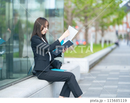 街角で書類を見る女性ビジネスウーマン 街角で書類を見る女性ビジネスウーマン 115685119