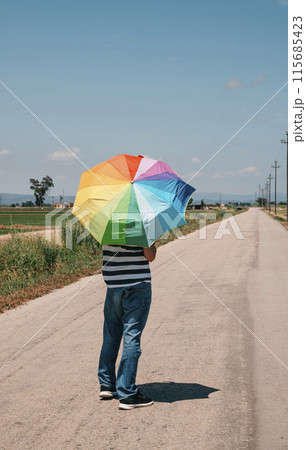 person carrying a rainbow umbrella 115685423
