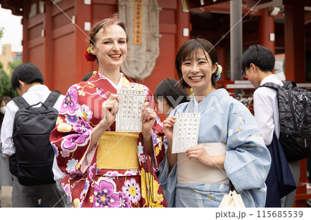 おみくじを見て喜ぶ着物姿の外国人女性と案内する日本人女性 おみくじを見て喜ぶ着物姿の外国人女性と案内する日本人女性 115685539
