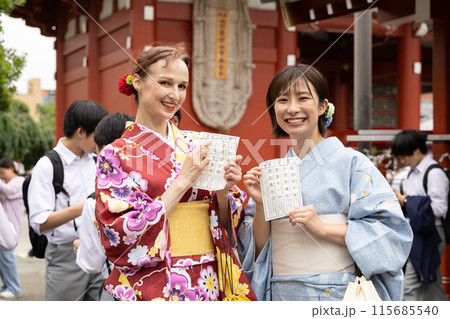 おみくじを見て喜ぶ着物姿の外国人女性と案内する日本人女性 115685540